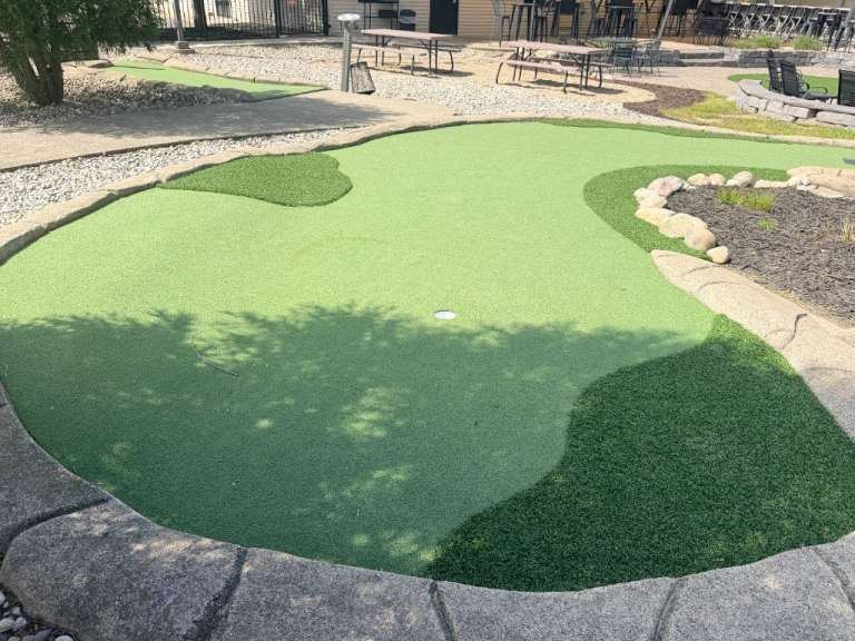 A nine-hole mini golf green with tree shade at Presidential Brewing