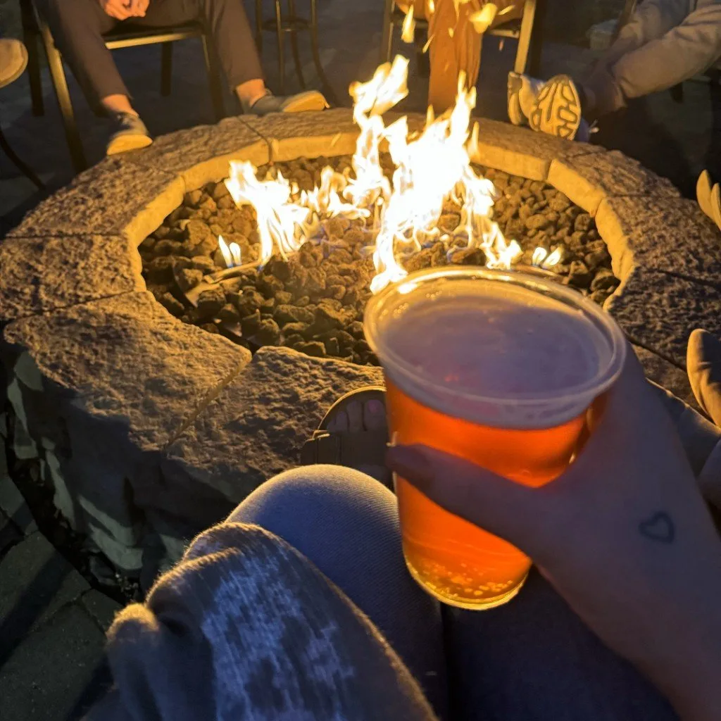 A pint held beside the fire pit after dark